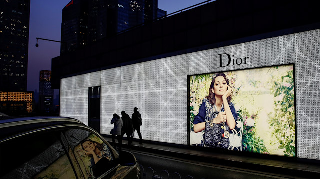 People walk past an advertising display of the Dior luxury goods company outside a department store in Beijing, China, November 30, 2016. Picture taken November 30, 2016. REUTERS/Thomas Peter

