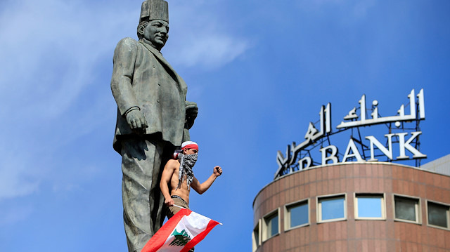 A demonstrator gestures while standing at Riad al-Solh statue during an anti-government protest