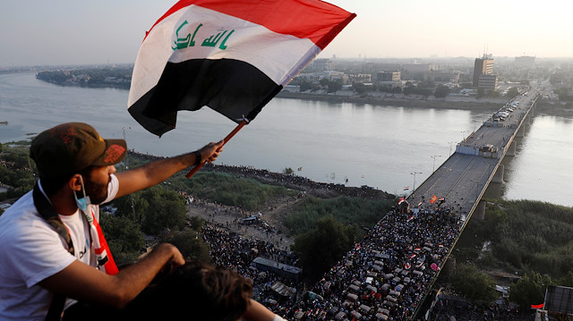 File photo: A demonstrator holds an Iraqi flag as he sits on a building during an anti-government protests in Baghdad, Iraq October 30, 2019