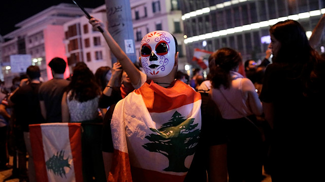 A protester carries a mask in the back of his head as he walks among fellow protestors at a demonstration a broadcasted interview by Lebanese President Michel Aoun, during ongoing anti-government protests in Beirut, Lebanon November 12, 2019. Picture taken November 12, 2019. REUTERS/Andres Martinez Casares

