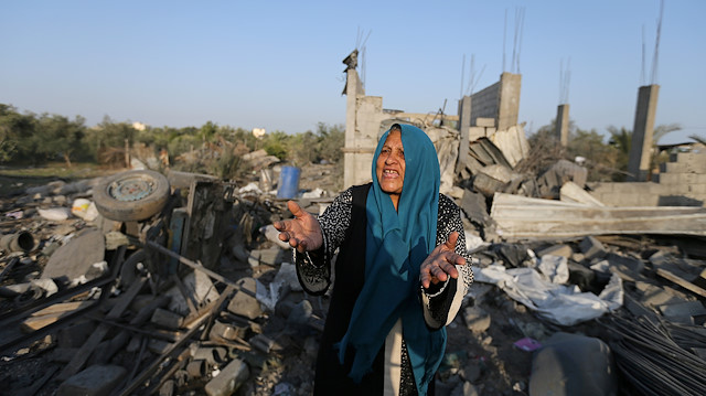 A Palestinian woman reacts as she inspects a house destroyed in an Israeli air strike in the southern Gaza Strip
