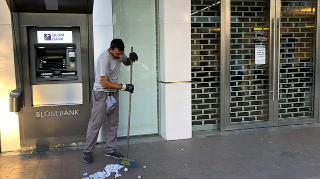 A worker cleans receipts from an ATM machine outside a closed Blom bank branch