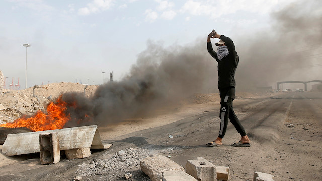Iraqi protesters burn tires as they block the entrance to Umm Qasr Port, south of Basra