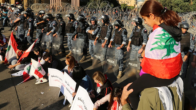 A girl has the national flag draped over her shoulders as riot police stand guard