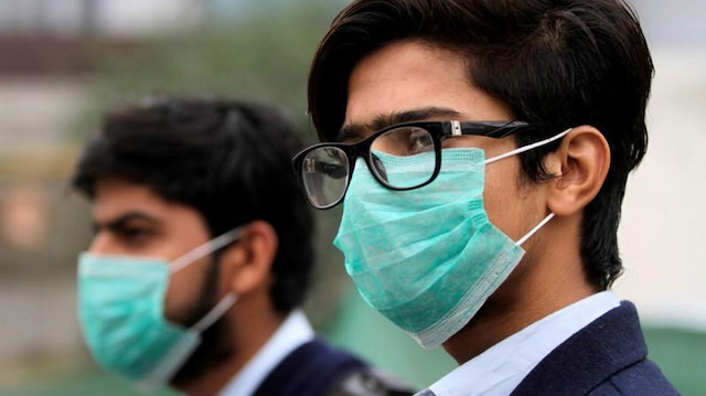 Men wearing protective masks wait for a bus in Lahore, Pakistan November 22, 2019.