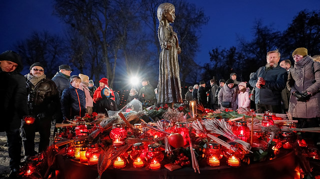 People visit a monument to Holodomor victims during a commemoration ceremony 