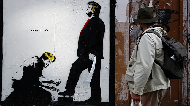 A man walks past graffiti depicting British Prime Minister Boris Johnson and U.S. President Donald Trump in London, Britain, November 7, 2019. REUTERS/Hannah McKay 
