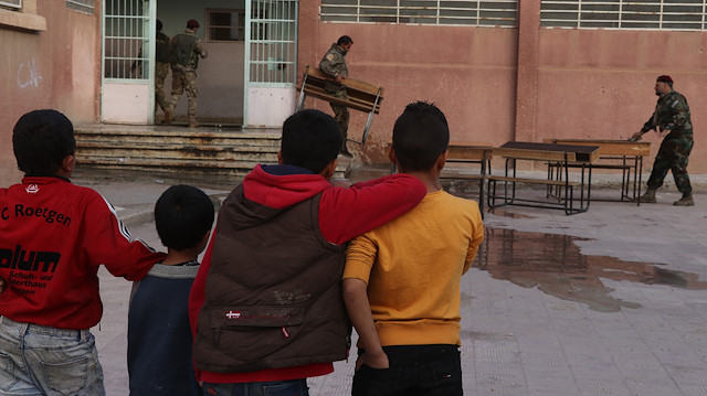 Askerler sıraları taşırken, çocuklar okullarına yapılan tadilatı keyifle izledi.