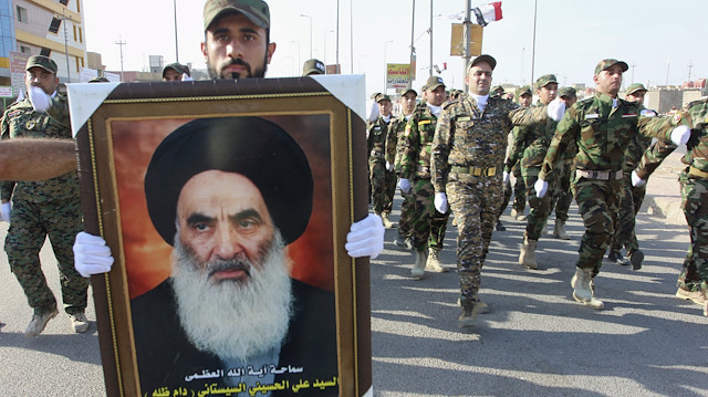 A member of Hashid Shaabi (Popular Mobilisation Forces) carries a portrait of Iraqi Shi'ite cleric Grand Ayatollah Ali al-Sistani during a military parade in Basra, southeast of Baghdad September 26, 2015. REUTERS/Essam Al-Sudani

