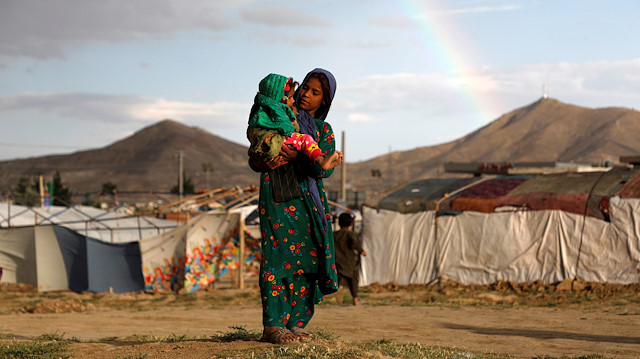 File photo: Internally displaced Afghan girl carries a child