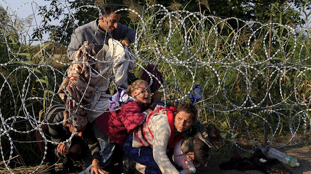  Syrian migrants cross under a fence as they enter Hungary at the border