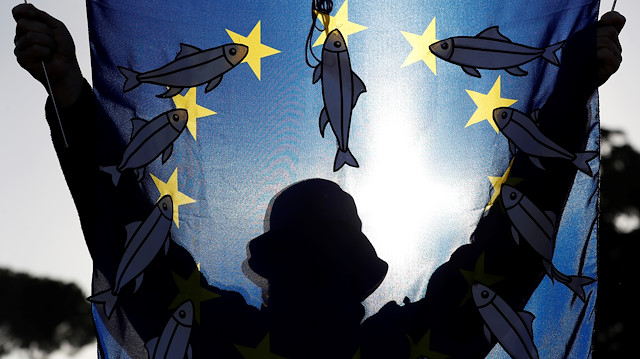 A man is seen through an EU flag decorated with paper sardines during a demonstration held by "the sardines", a grassroots movement against far-right League leader Matteo Salvini, in Rome, Italy, December 14, 2019. REUTERS/Yara Nardi
