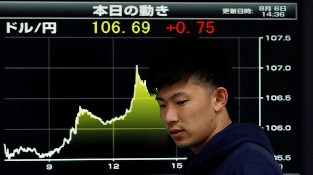 FILE PHOTO: An employee of a foreign currency company walks past in front of a graph showing recent movements of the exchange rates between the Japanese yen and the U.S. dollar at a dealing room in Tokyo, Japan, August 6, 2019. REUTERS/Issei Kato/File Photo


