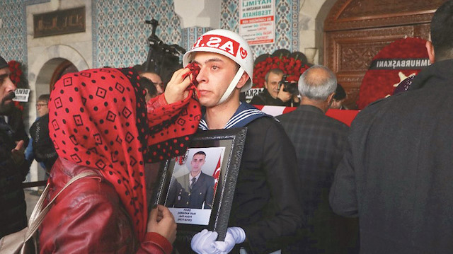 Törende şehidin fotoğrafını tutan asker gözyaşlarına hakim olamazken, askerin gözyaşlarını şehit yakınları sildi.