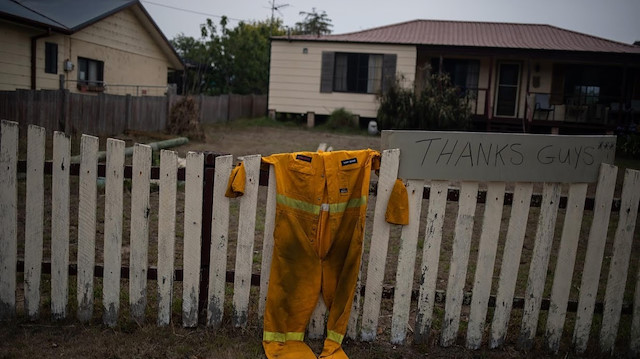 A firefighter's suit hangs on the fence of a property.
