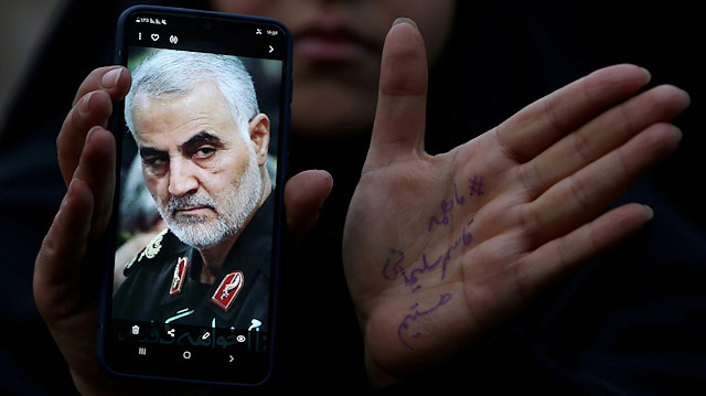 An Iranian woman shows a photo of the late Iranian Major-General Qassem Soleimani 