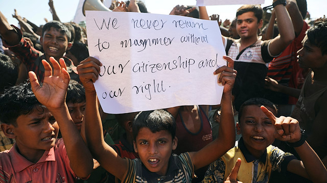 A boy holds a placard as hundreds of Rohingya refugees protest 