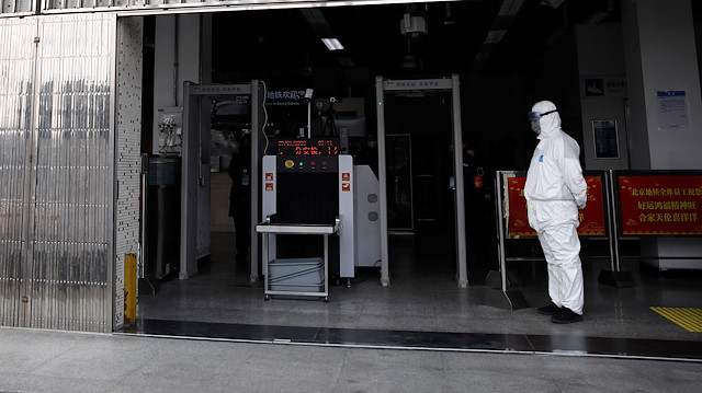 A worker in protective suit stands at the entrance of the Xizhimen subway station