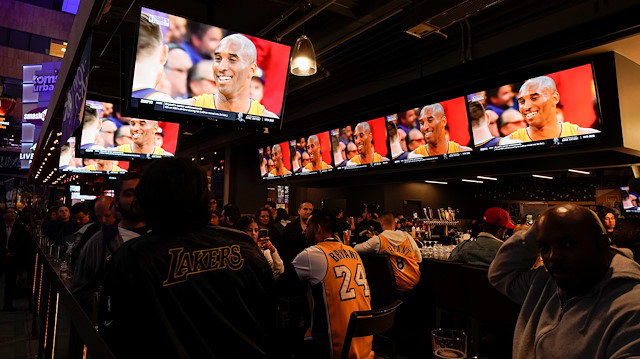 Fans of NBA basketball star Kobe Bryant watch a replay of his last NBA game as they sit at an outdoor bar near the Staples Center at L.A. Live in Los Angeles, California, U.S., January 27, 2020. REUTERS/Mike Blake

