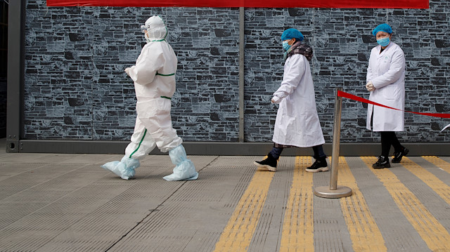 Hospital staff in protective garments walk at a checkpoint 