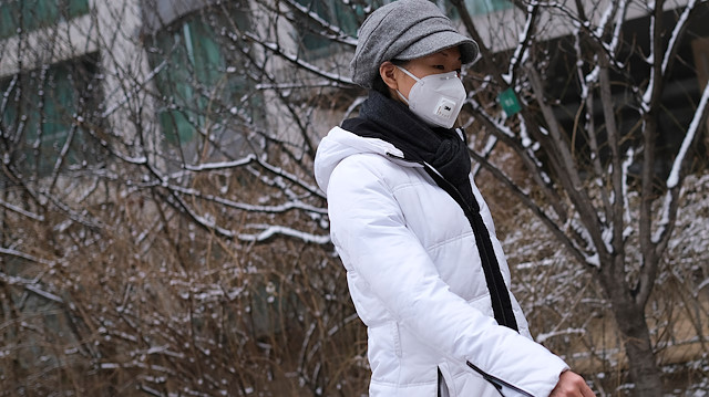 A woman wearing a face mask walks at a residential complex after a snowfall, as the country is hit by an outbreak of the new coronavirus, in Beijing, China February 2, 2020. REUTERS/Carlos Garcia Rawlins

