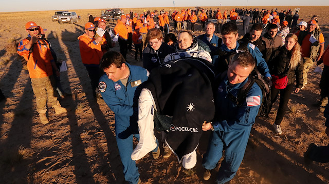 Ground personnel carry International Space Station (ISS) crew member Ricky Arnold