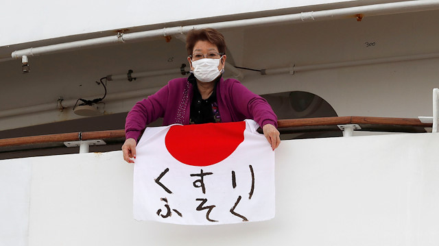 A woman holds a Japanese flag that reads "shortage of medicine" on the cruise ship Diamond Princess, where 10 more people were tested positive for coronavirus on Thursday, to the port as it is anchored at Daikoku Pier Cruise Terminal in Yokohama, south of Tokyo, Japan February 7, 2020. 