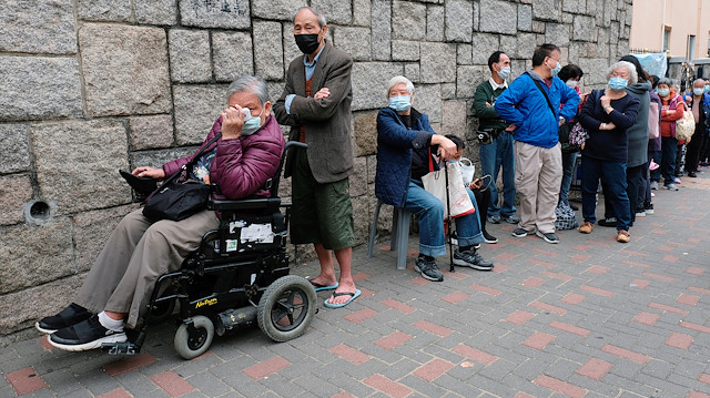 Yaşlılar bir marketten ücretsiz cerrahi maske almak için sıraya giriyor. 