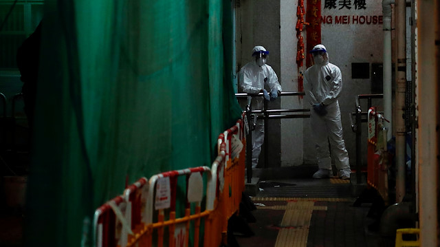 Koruyucu giysilerdeki uzmanlar, Hong Kong'da, yeni koronavirüsün patlak vermesinin ardından konut binasından sakinleri tahliye etmeye hazırlanıyor. 