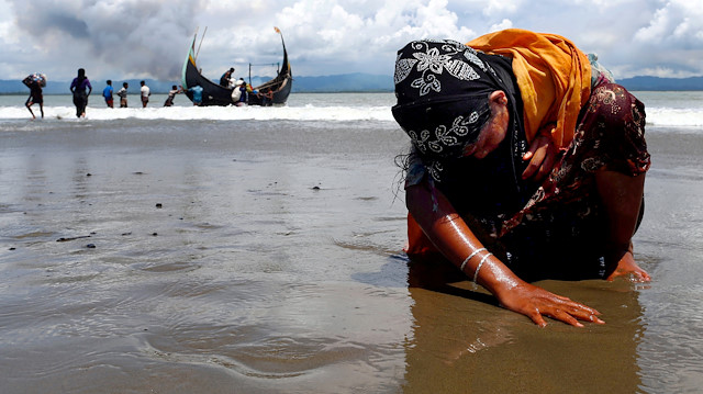 FILE PHOTO: An exhausted Rohingya refugee woman touches the shore after crossing the Bangladesh-Myanmar border by boat through the Bay of Bengal, in Shah Porir Dwip, Bangladesh September 11, 2017. REUTERS/Danish Siddiqui/File Photo

