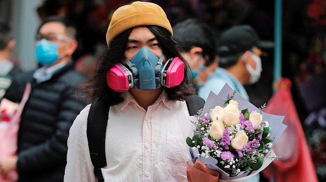 A man wears a gas mask as he holds a bouquet of flowers, following the outbreak of the novel coronavirus on Valentine’s Day in Hong Kong, China February 14, 2020. REUTERS/Tyrone Siu

