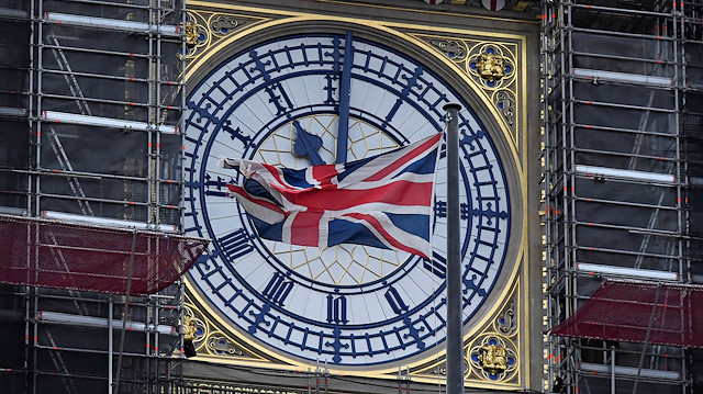 The British union flag is seen fluttering as the clock face of Big Ben shows eleven o'clock