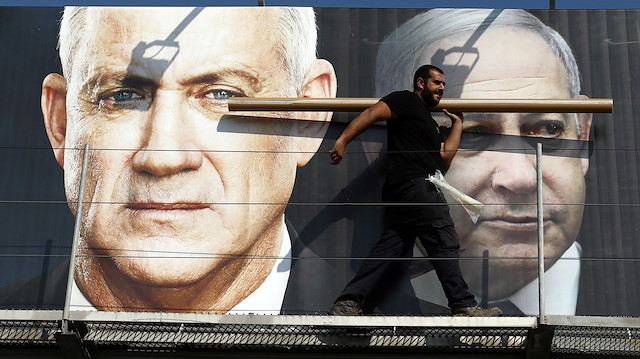 Bir işçi, Tel Aviv'de İsrail'in önümüzdeki seçim kampanyasının bir parçası olarak İsrail Başbakanı Netanyahu ve Mavi ve Beyaz partinin lideri Gantz'ı tasvir eden bir pankart asıyor. 