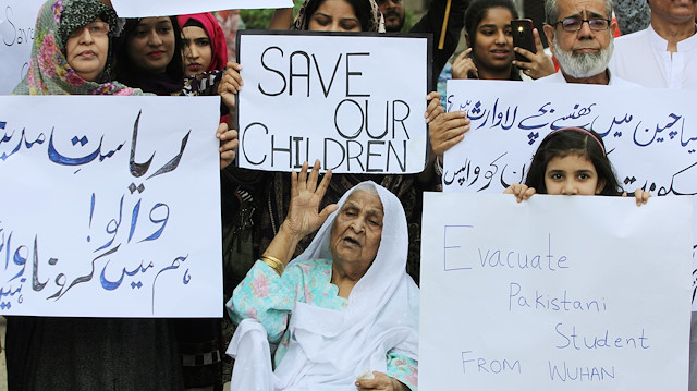 Family members hold signs demanding the evacuation of Pakistani students from Wuhan 