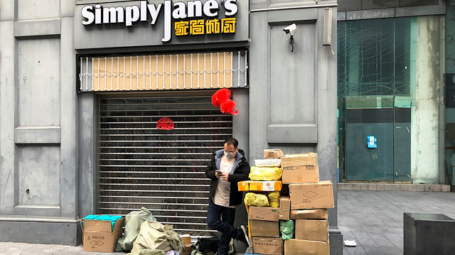 A man wearing a face mask checks his mobile phone next to a trolley of boxes on the streets of Huaqiangbei, the world's largest electronics market, following an outbreak of the novel coronavirus in the country, in Shenzhen, Guangdong province, China February 18, 2020. Picture taken February 18, 2020
