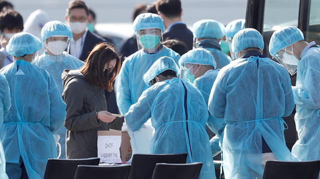 File photo: Workers in protective gear assist a passenger in a face mask after she leaves the coronavirus-hit cruise ship Diamond Princess at Daikoku Pier Cruise Terminal in Yokohama, south of Tokyo, Japan February 21, 2020

