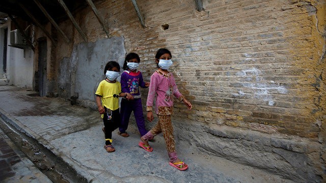 Iraqi children wear protective masks as they walk near a religious school