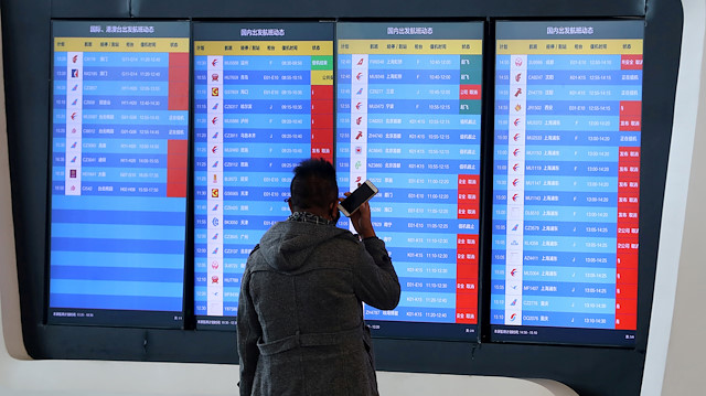 File photo: A man stands in front of a screen showing that multiple departure flights have been cancelled after the city was locked down following the outbreak of a new coronavirus, at an airport in Wuhan, Hubei province, China