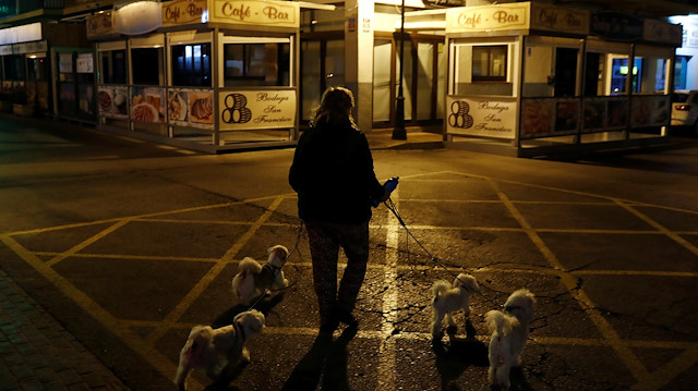 File photo: A woman walks with her dogs towards her home after a walk past an empty terrace of bar as people remain confined inside their homes due to the coronavirus outbreak, in downtown Ronda, southern Spain March 14, 2020