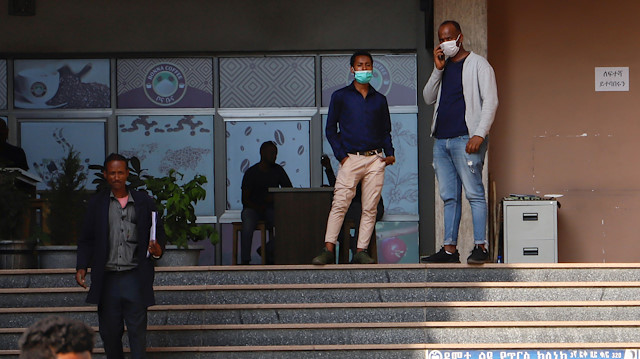 Men wearing protective masks stand in front of a cafeteria after the first coronavirus cas