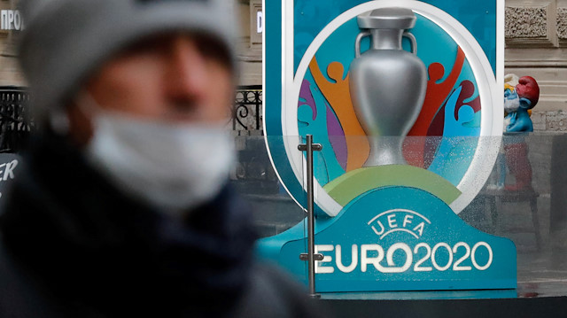 FILE PHOTO: A person wearing a protective face mask walks past the Euro 2020 countdown clock, as the number of coronavirus (COVID-19) cases worldwide continues to grow, in central Saint Petersburg, Russia March 16, 2020