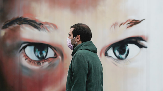 FILE PHOTO: A man wearing a protective mask walks outside a hospital during the partial lockdown as part of a 15-day state of emergency following the coronavirus outbreak in Madrid, Spain March 17, 2020
