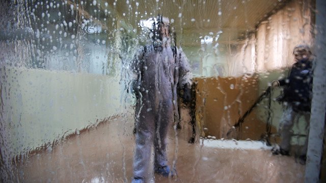 A worker wearing a protective suit disinfects a bus station, following the outbreak of covid-19