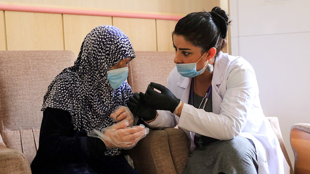 A nurse talks with an elderly woman as she wears a face mask amid fears of coronavirus 