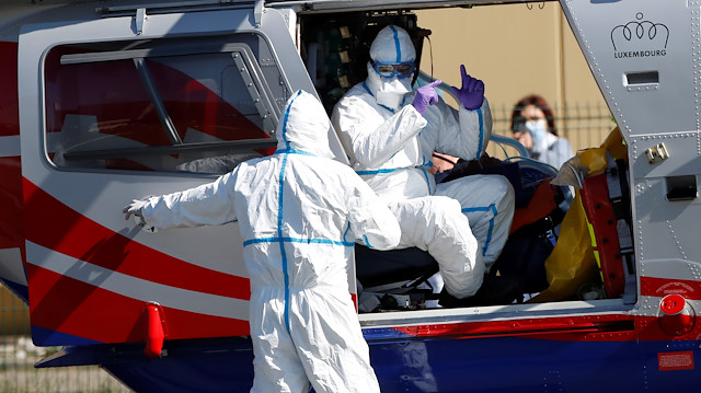 French rescue team wearing protective suits evacuate a patient from Mulhouse hospital