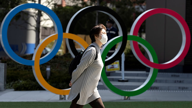 FILE PHOTO: A woman wearing a protective face mask, following an outbreak of the coronavirus disease (COVID-19), walks past the Olympic rings in front of the Japan Olympics Museum in Tokyo, Japan March 13, 2020