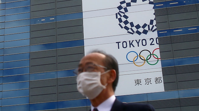 FILE PHOTO : A man, wearing a protective mask following an outbreak of the coronavirus disease (COVID-19) is pictured in front of a banner for the upcoming Tokyo 2020 Olympics in Tokyo, Japan, March 12, 2020