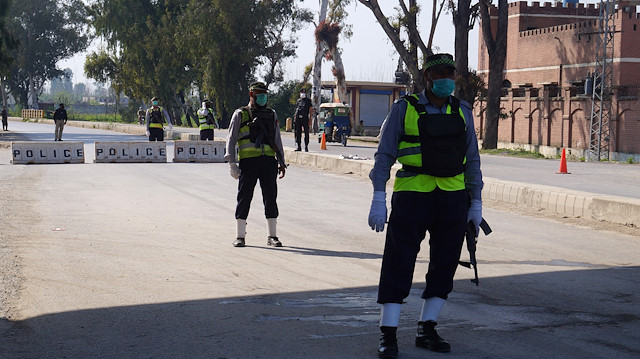 Police officers stand guard at a blocked road leading to Manga village after an outbreak of coronavirus disease (COVID-19), in Marden, Pakistan March 19, 2020