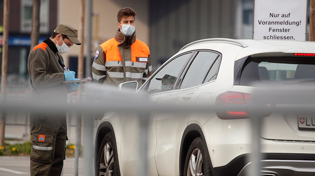 Civil defence workers wearing protection masks check the papers of a driver of a car 