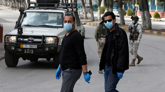People wear face masks at a check point in the northern governorate of Irbid